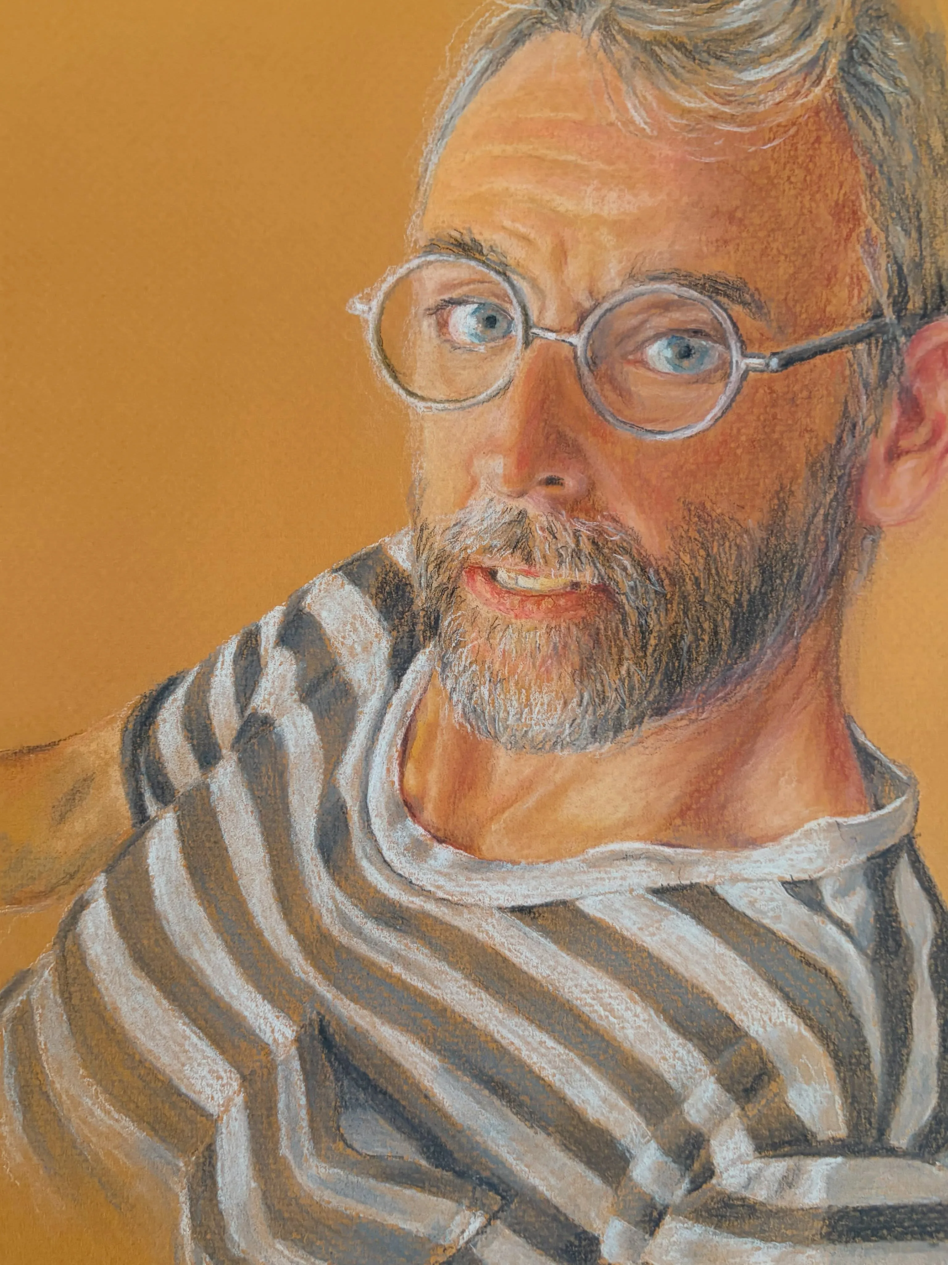 Portrait of a bearded man in round glasses and a striped top, glancing over his shoulder against an orange background