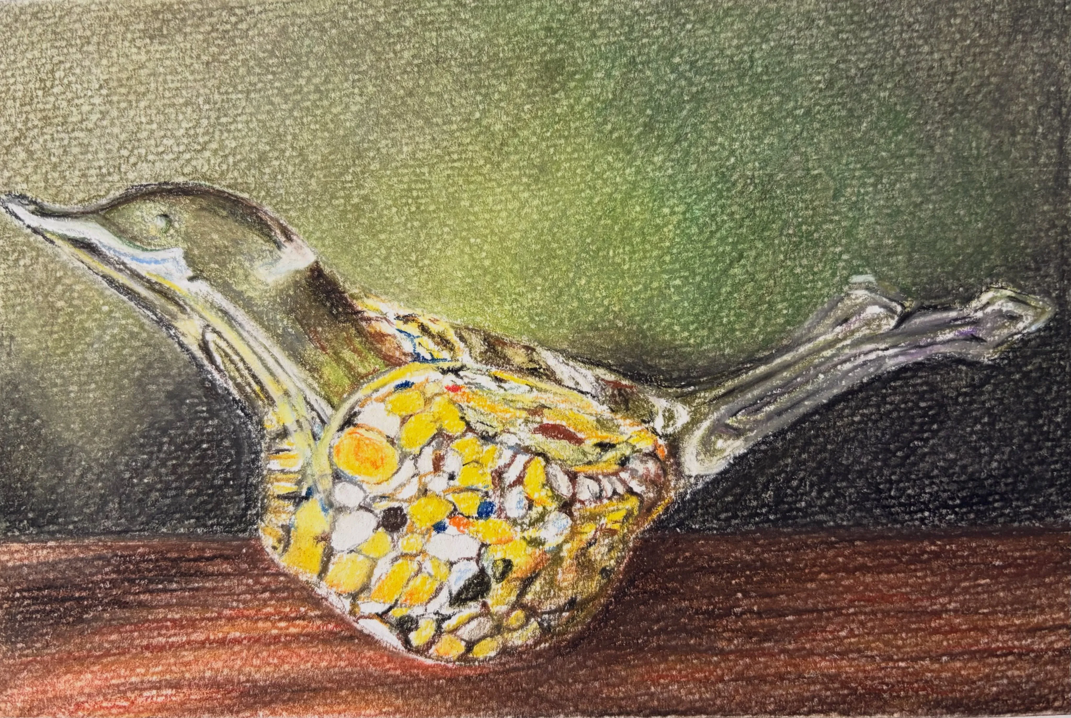 A speckled yellow glass bird ornament on a wooden surface against a dark green background